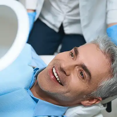 A man in dental chair looking in a mirror. 